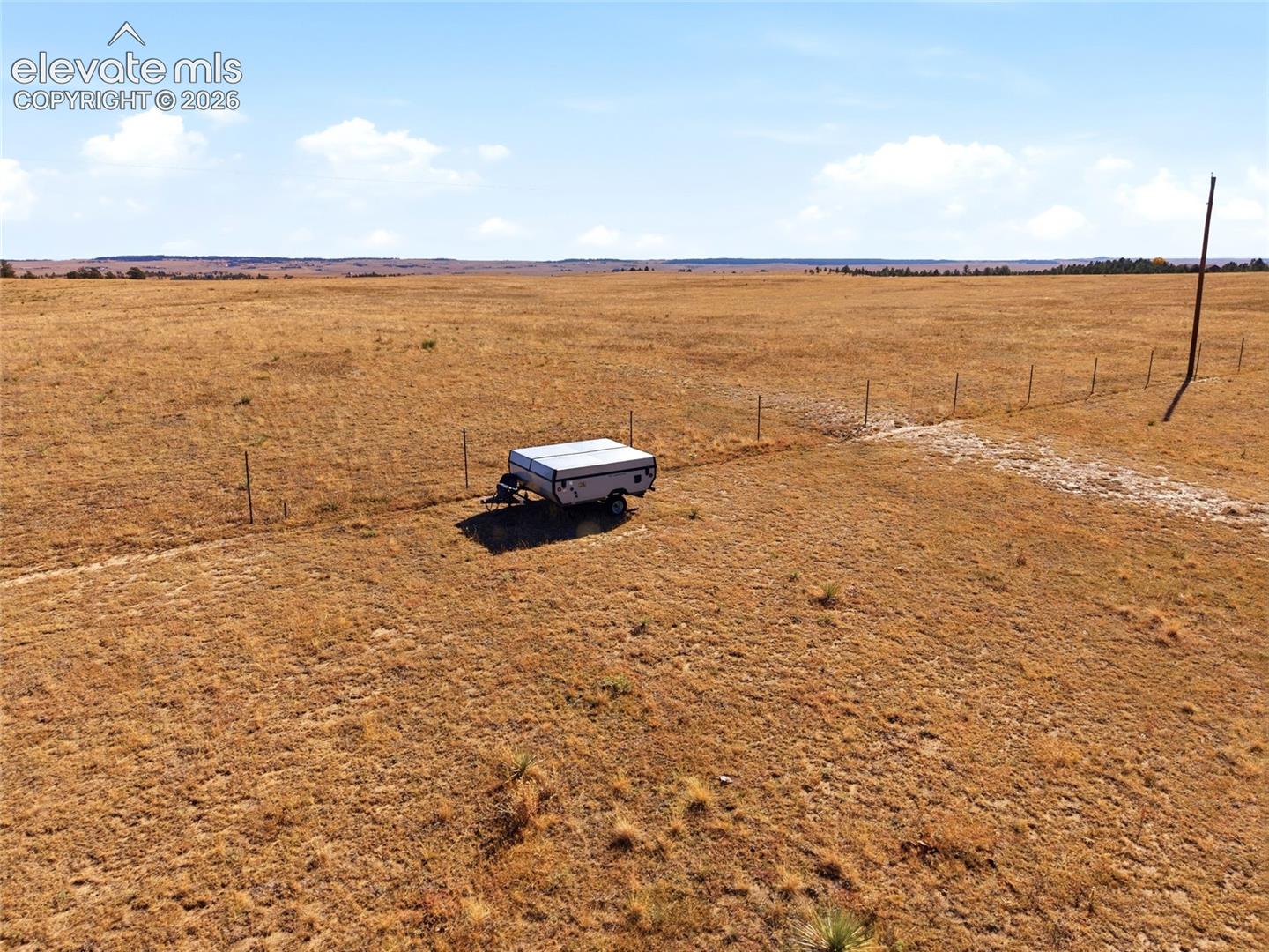 Expansive acreage featuring vast, open terrain, wire perimeter fencing, and a utility pole