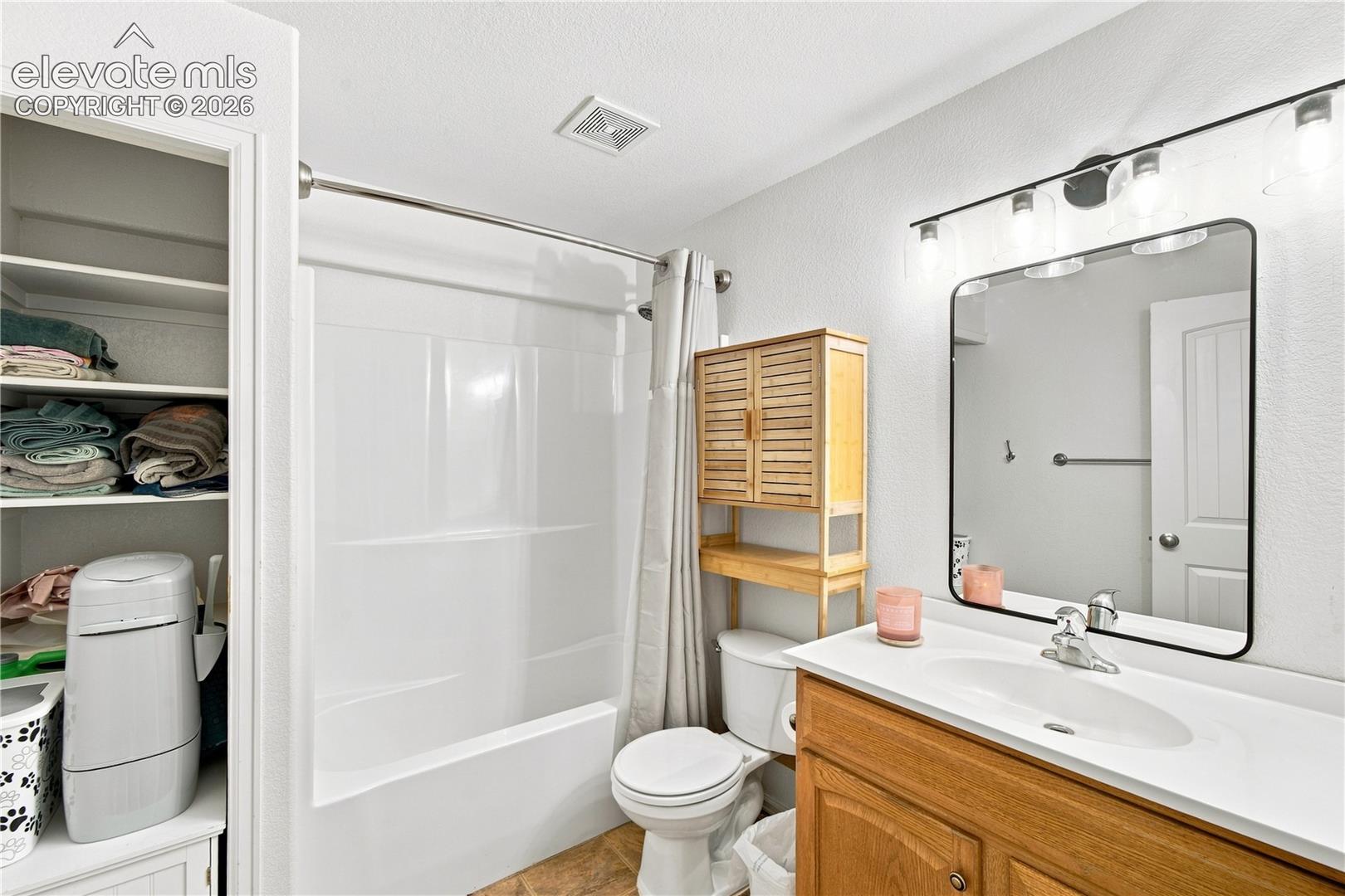 White vanity with integrated sink, wood-finish cabinetry, and a rectangular mirror with black trim