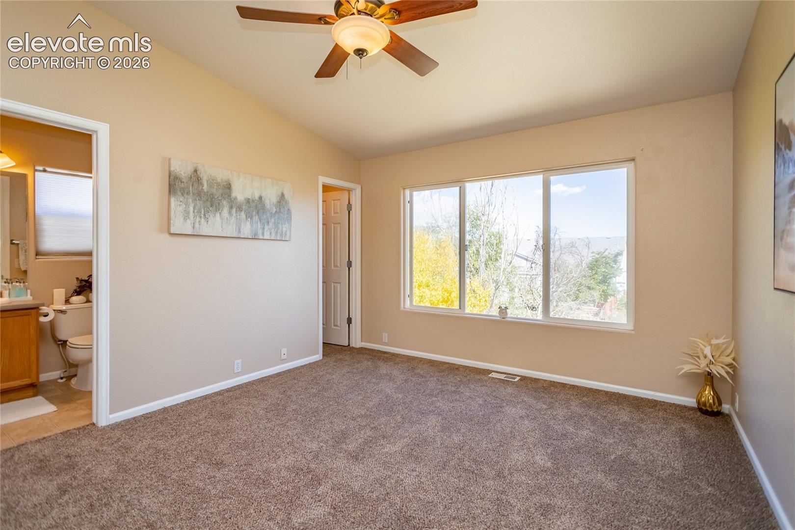  Large windows in the primary suite frame peaceful views while providing access to a private en-suite bathroom