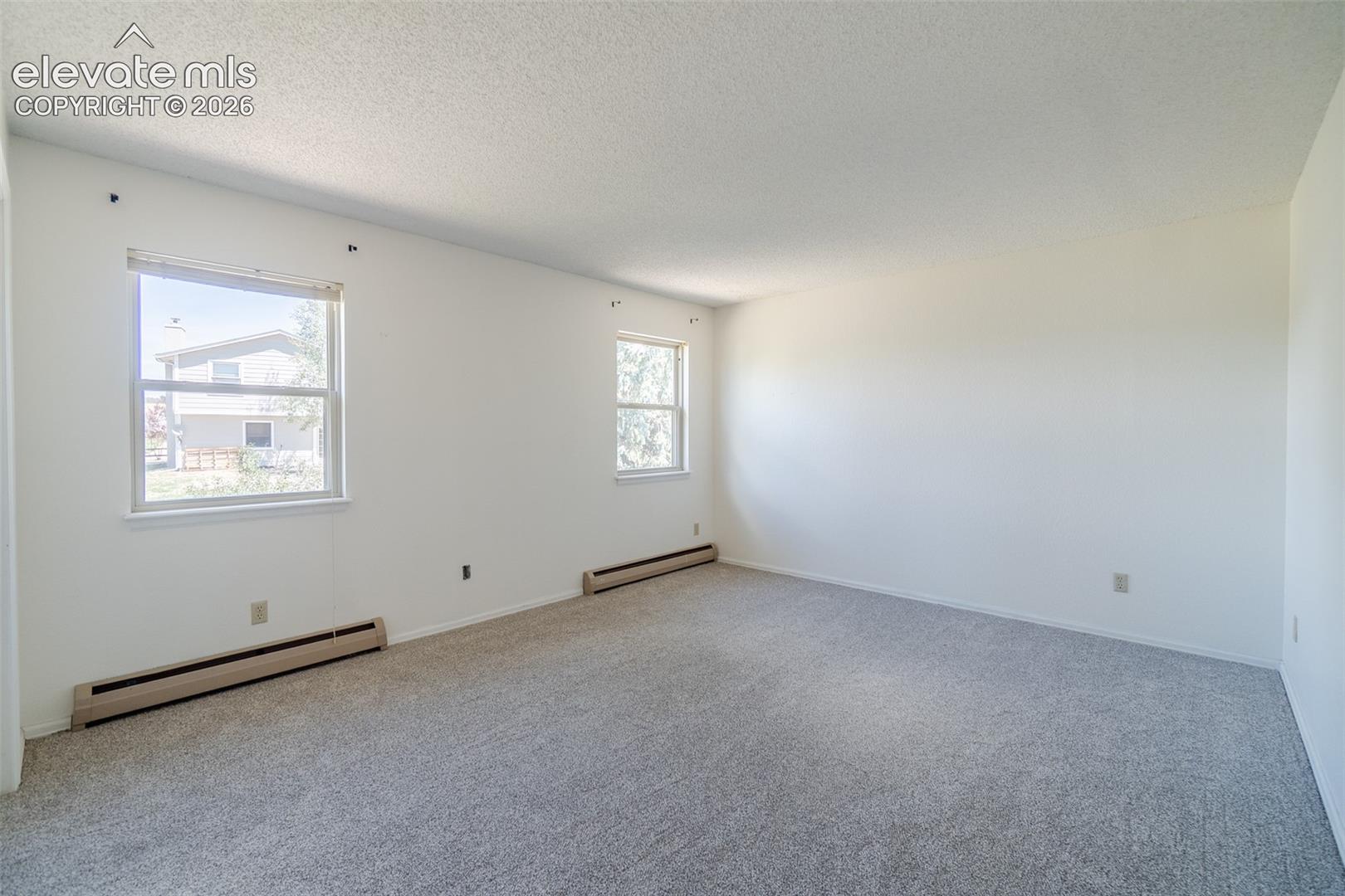 One of Four upstairs Spacious bedroom with brand new light-colored carpeting, white painted walls, baseboard heating and multiple windows