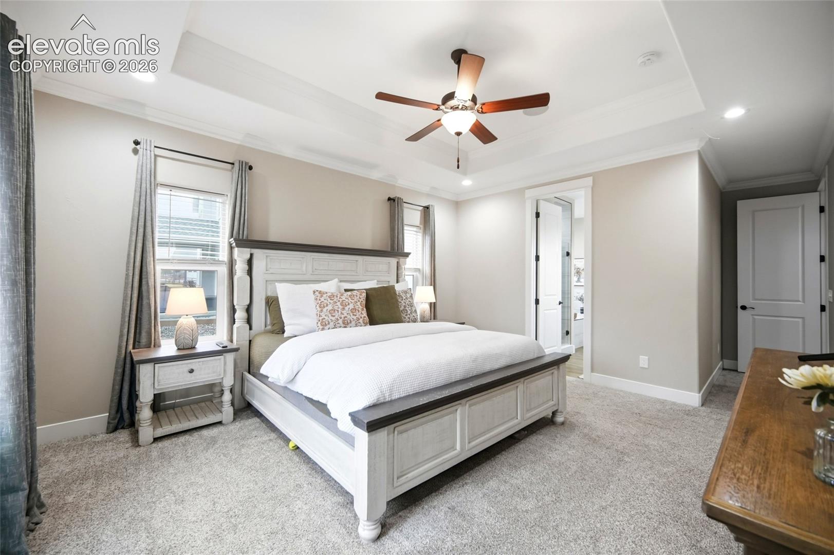Tray ceiling with recessed lighting, central ceiling fan, and neutral wall tones