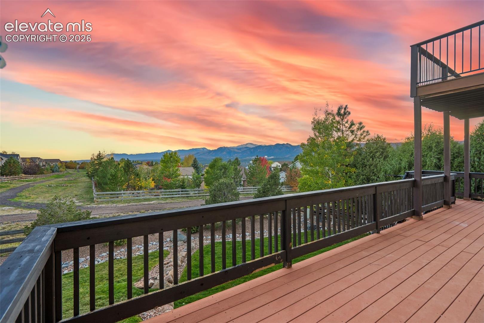 Multi-level deck featuring wood-finish decking, dark metal railings, and mountain scenery
