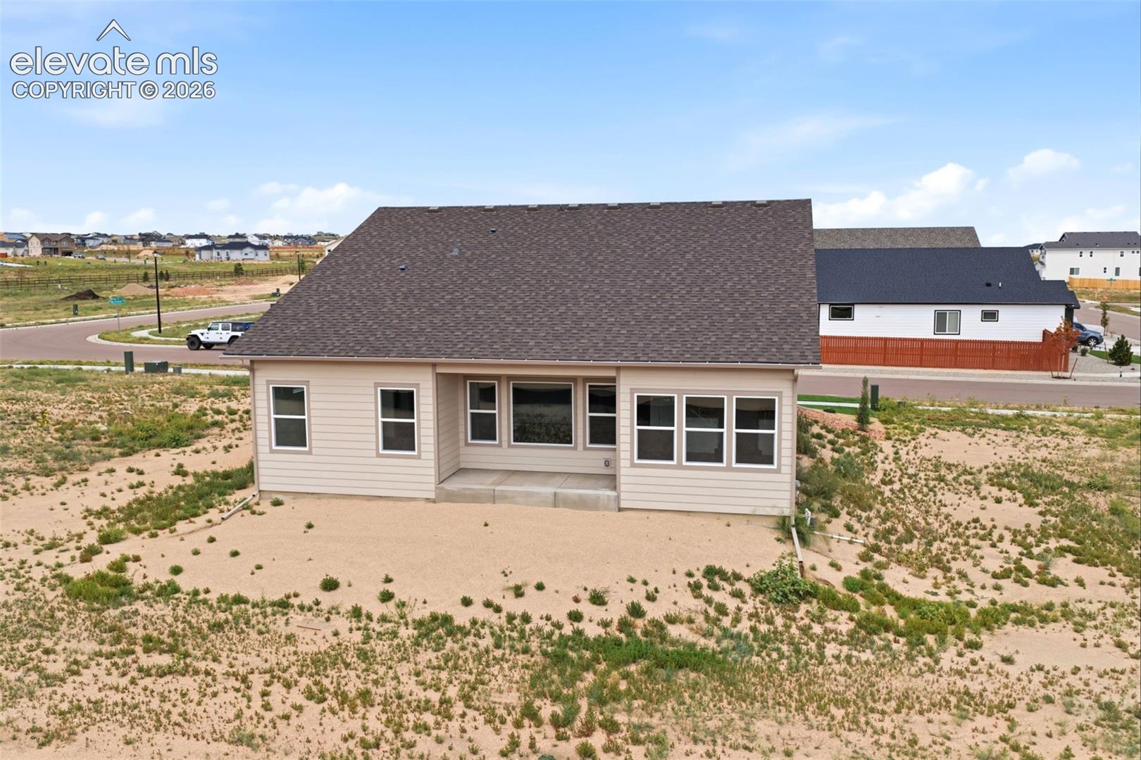 Single-story residence featuring light-toned horizontal siding, a pitched shingle roof, and a rear concrete patio