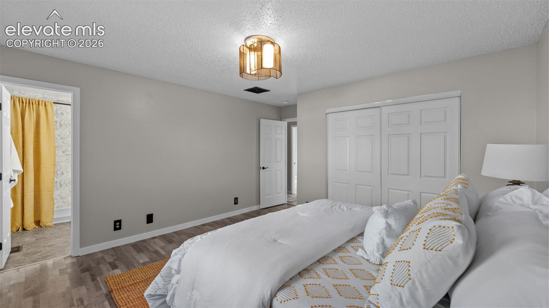 Room featuring wood-finish flooring, a multi-panel sliding closet, and a multi-light flush-mount ceiling fixture