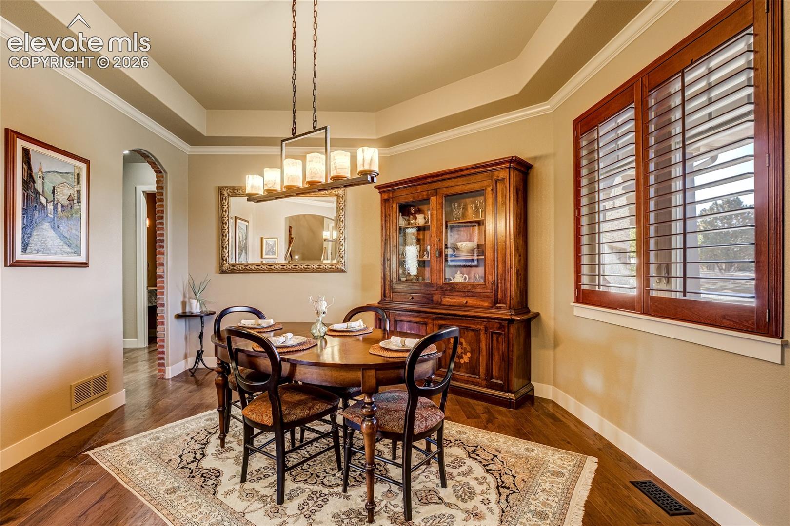 The formal dining room offers an elegant setting for holidays + special occasions, featuring substantial knotty alder crown molding, engineered wood flooring, refined architectural detailing + a statement chandelier.