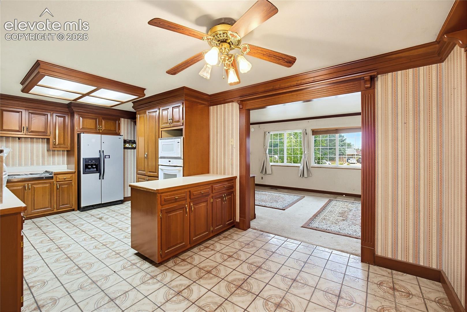 Kitchen featuring wood cabinetry, integrated oven and microwave, and tile flooring