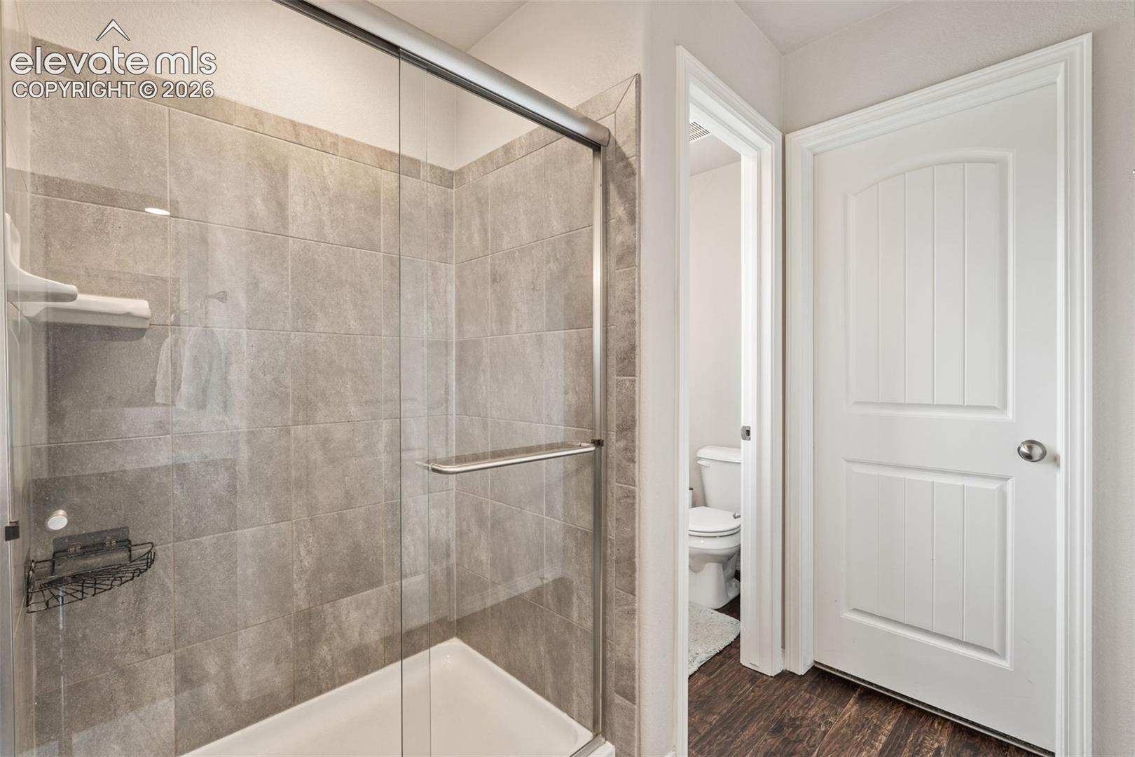 Shower with clear glass enclosure and light-toned tile surround