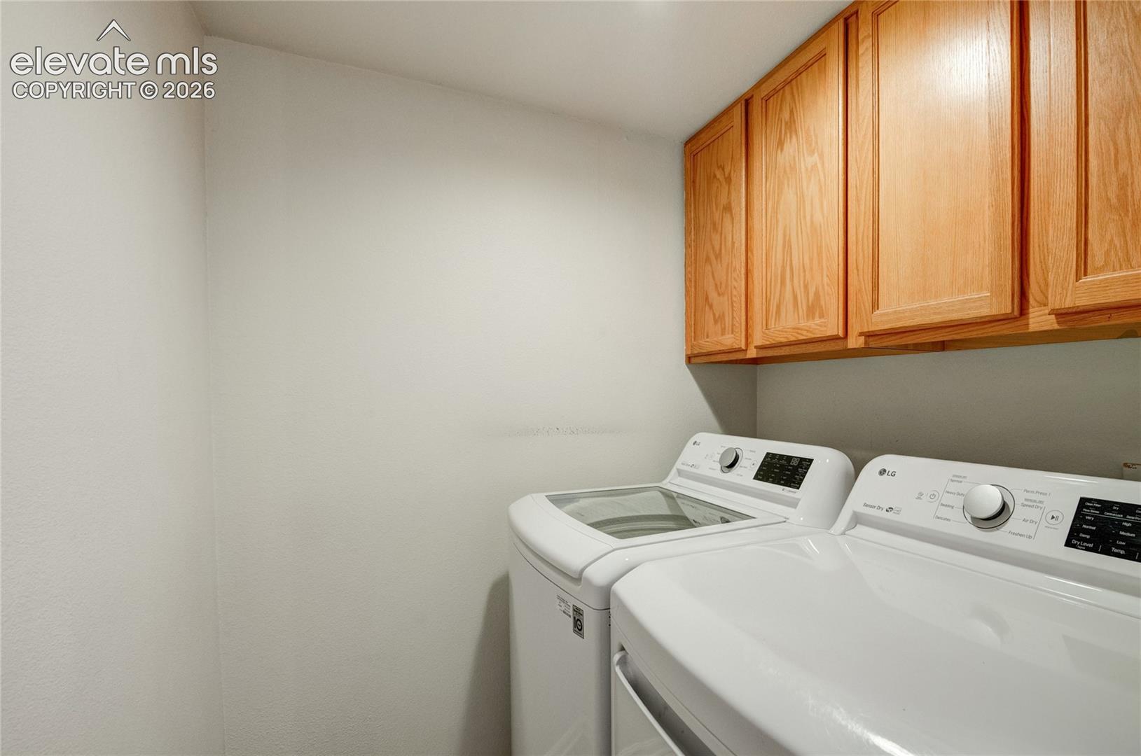 Dedicated laundry space featuring upper wood cabinetry