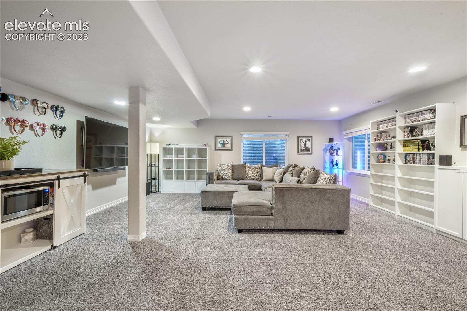 Recessed lighting, wood-finish flooring, built-in shelving, and white baseboards