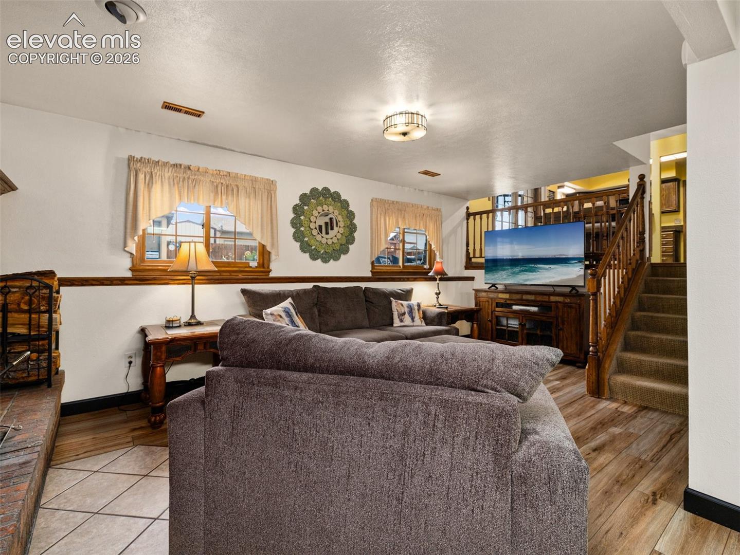 Wood-finish flooring, tiled fireplace hearth, and a wood staircase with carpeted treads