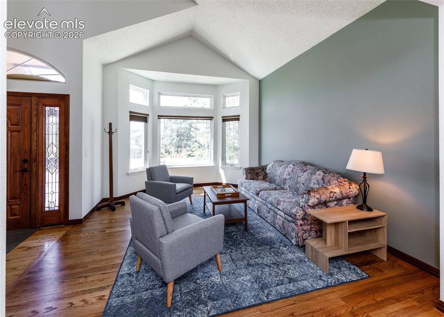 Vaulted ceilings, wood-finish flooring, bay windows, leaded glass front door, and a built-in coat rack