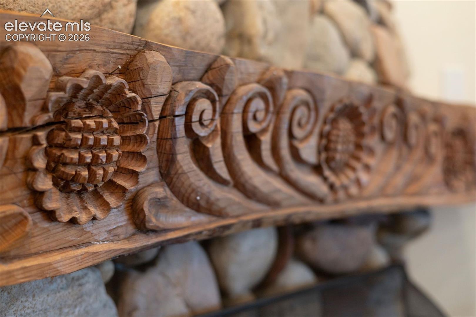Detailed mantle featuring intricate pinecone and scroll detailing, an undeniable focal point of the room. 
