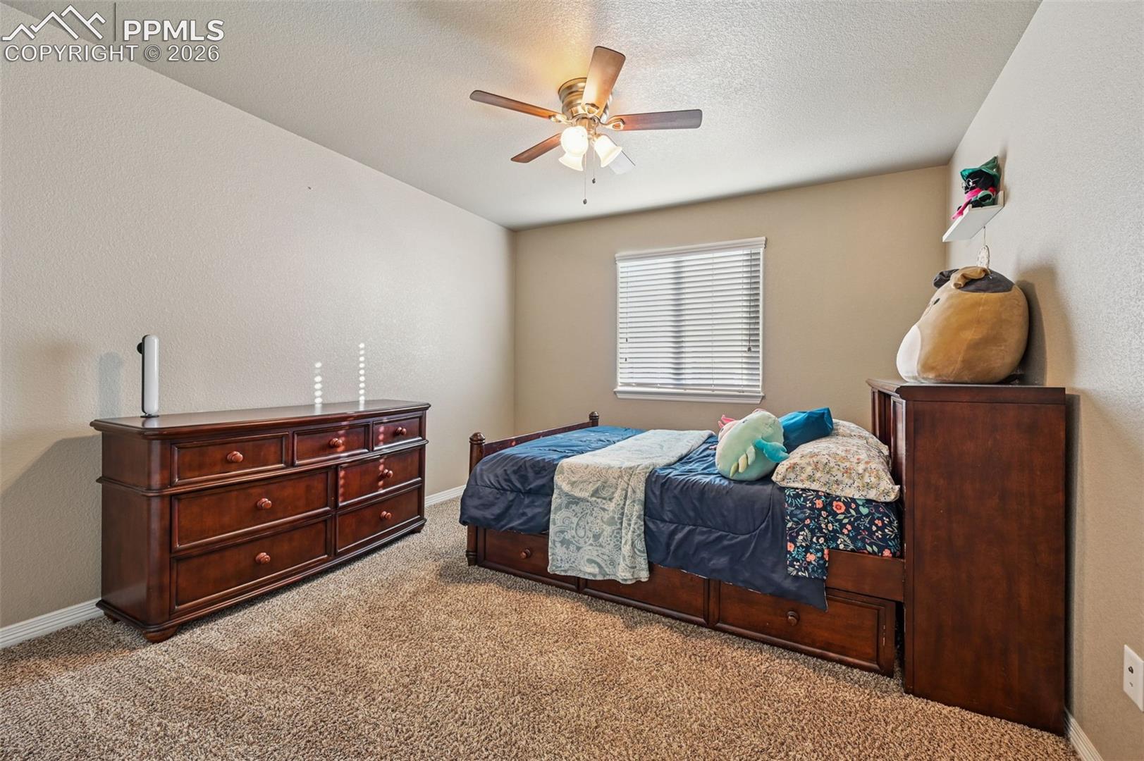 Carpeted bedroom featuring a ceiling fan, a textured wall, and a textured ceiling