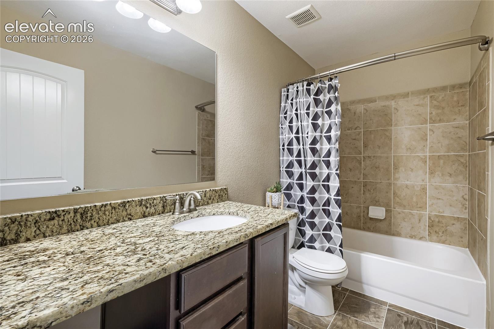 Upper-level hall full bathroom featuring a vanity with a light-toned patterned countertop and an undermount sink