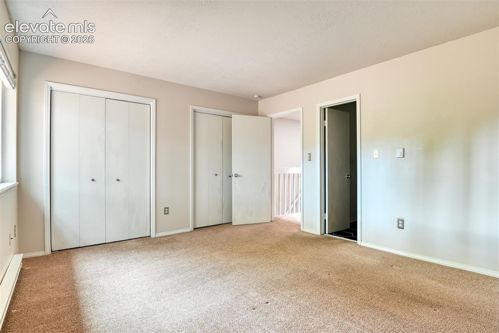 Wall-to-wall carpeting with light-toned walls, white trim, and a window