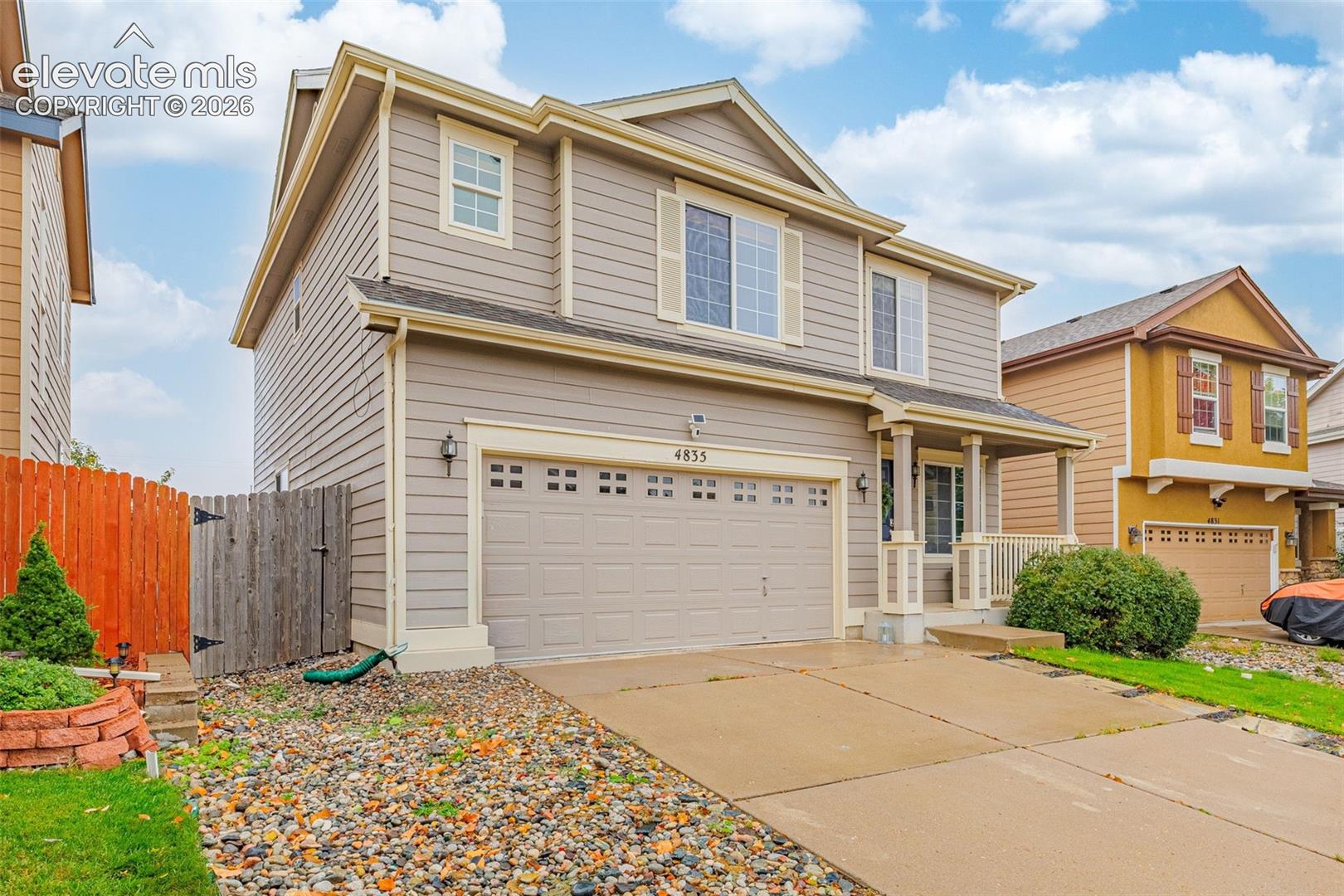 Two-story residence featuring horizontal siding, a covered front porch with decorative columns, and an attached two-car garage with paneled doors