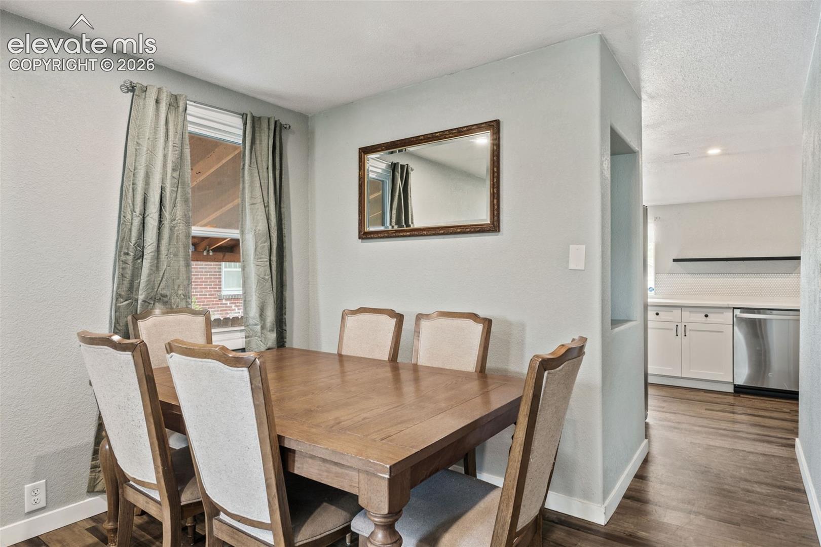 Dining area featuring wood-finish flooring, a rectangular window with drapes, and a wall niche