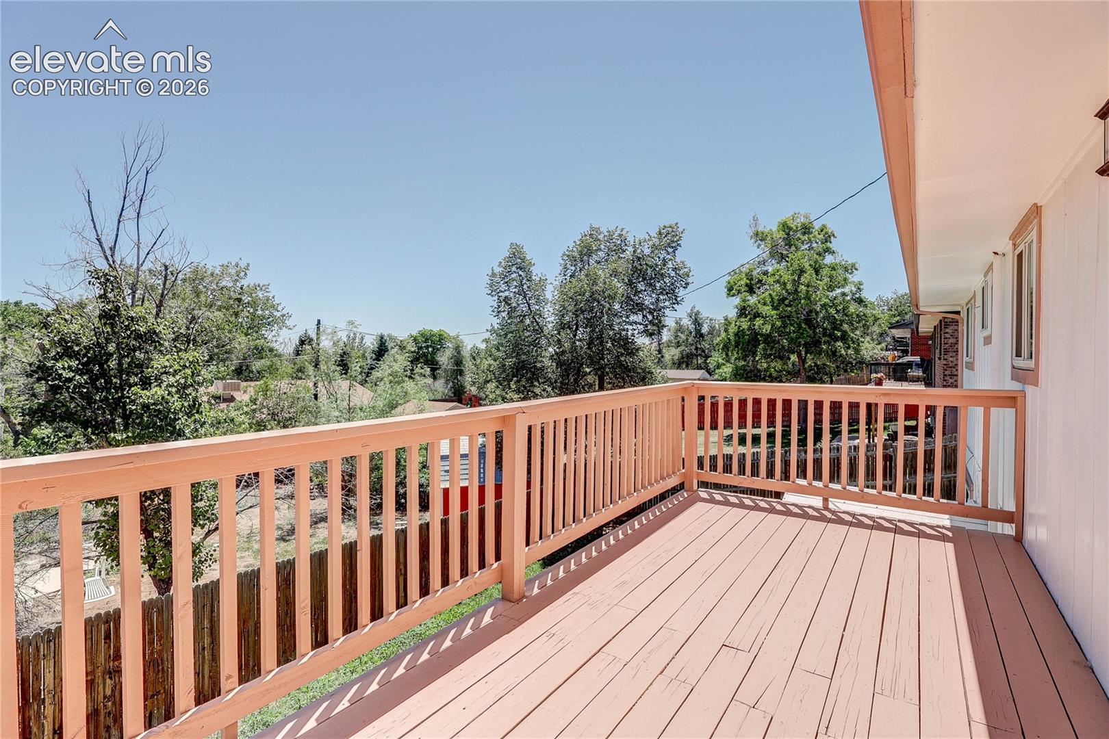 Elevated wooden deck featuring vertical baluster railings and expansive outdoor space