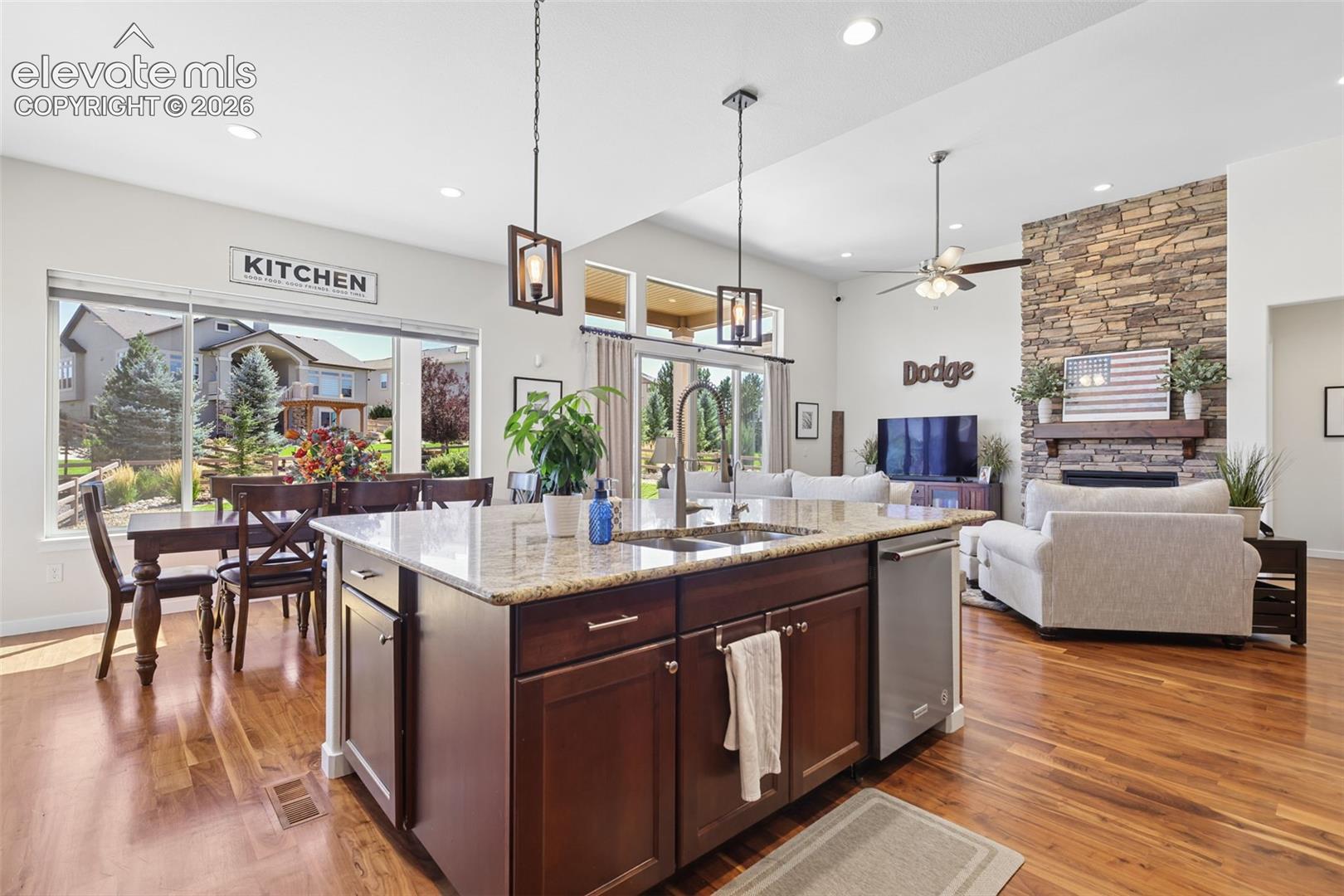 Open-concept interior with wood-finish flooring, a kitchen island with stone countertop, and recessed lighting