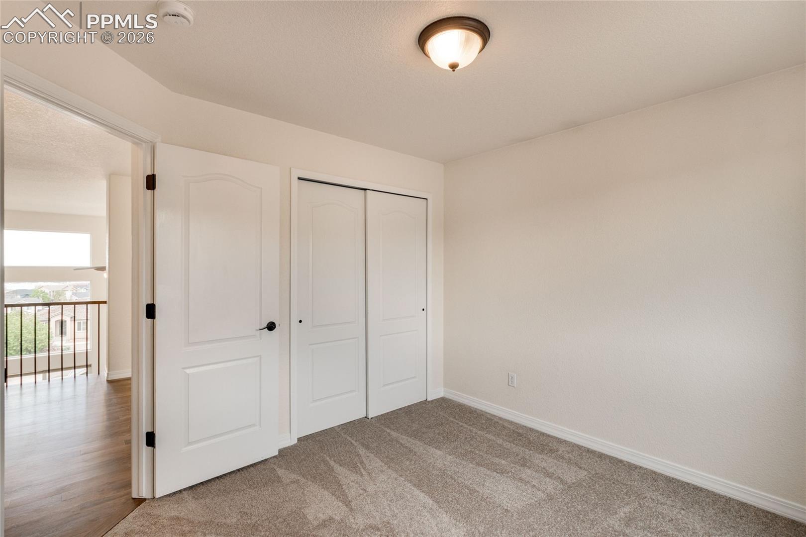 Second upstairs bedroom with white walls and a closet with sliding doors.