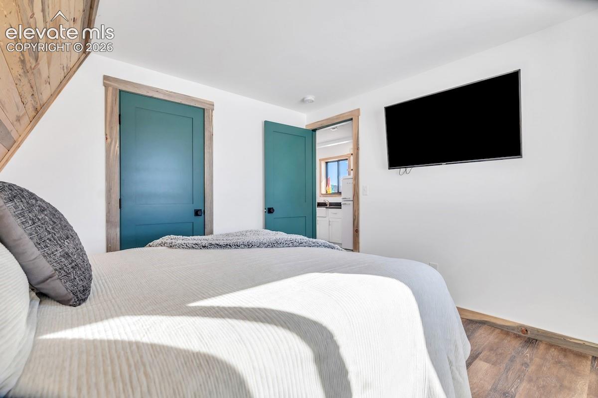 Wood-finish flooring, angled wood-paneled ceiling, and teal-painted interior doors with natural wood trim