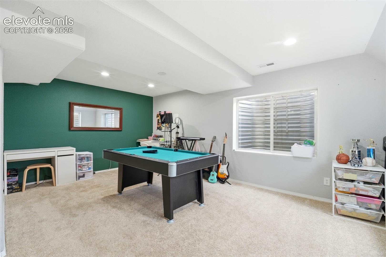 Recreational room featuring a deep green accent wall and a large window