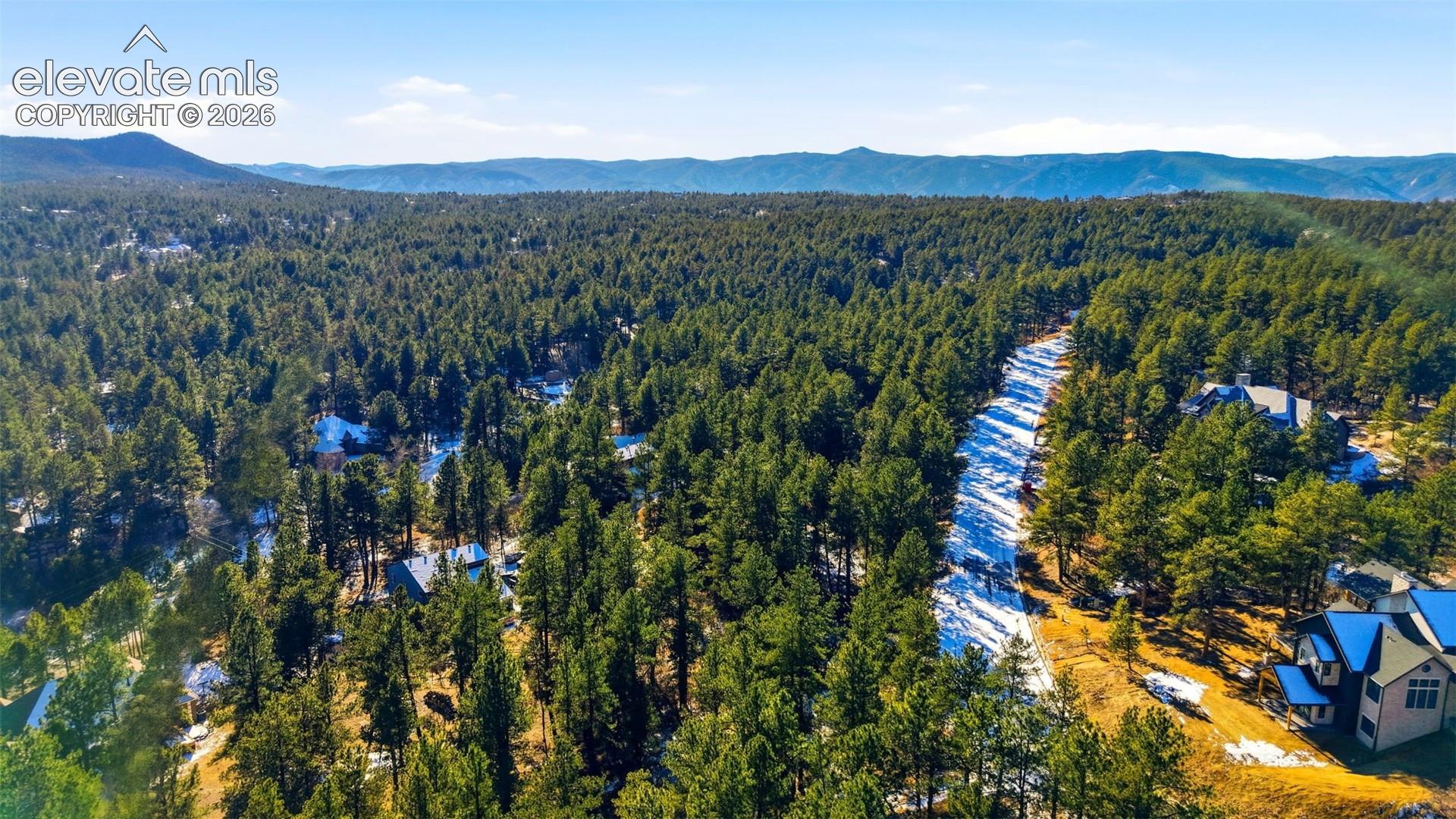 Expansive forested landscape with distant mountain ranges and scattered residential structures