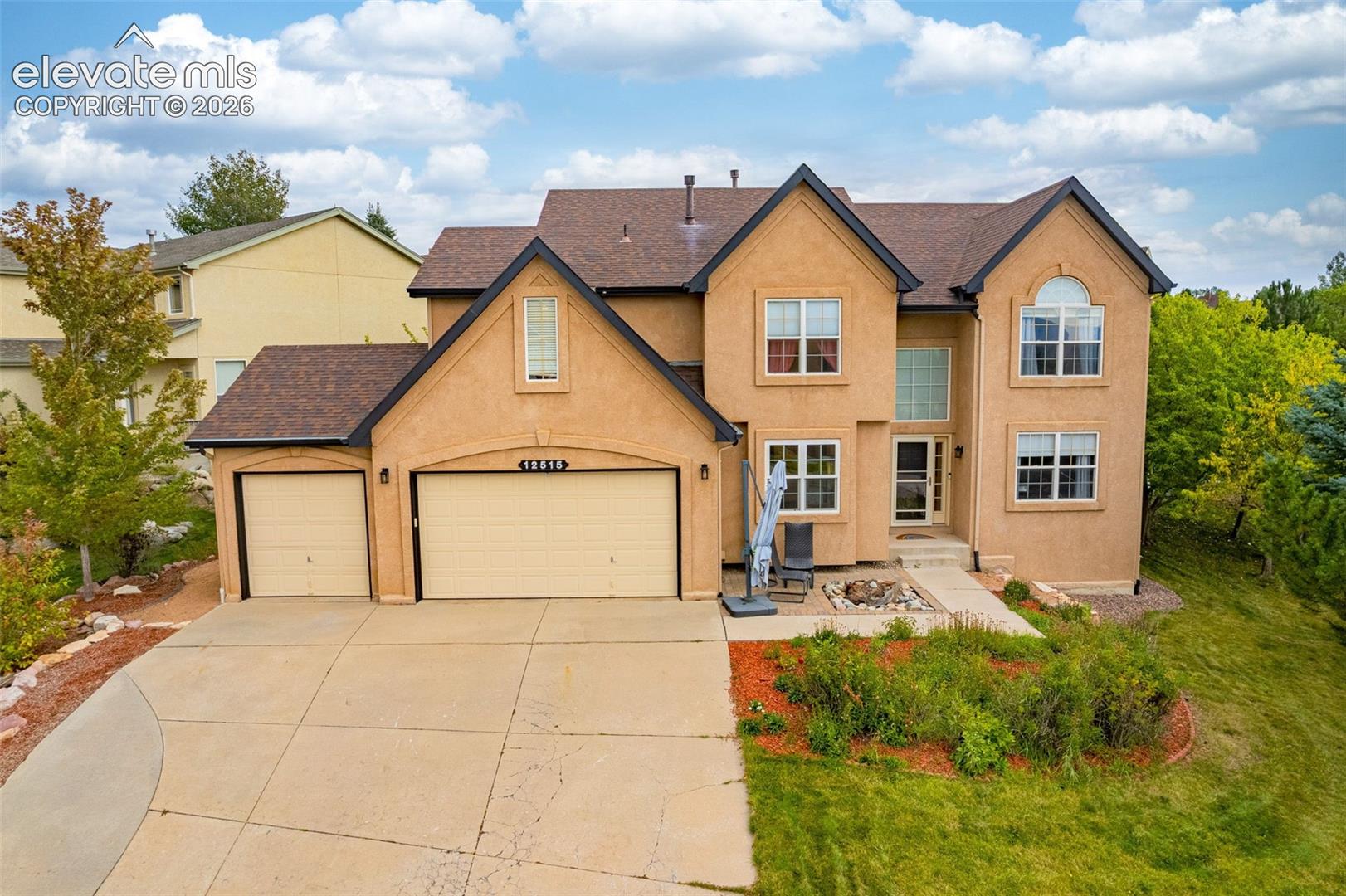 Stucco exterior with a multi-level roofline, prominent gables, an attached three-car garage, and a concrete driveway