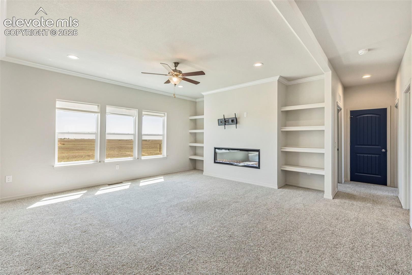 Bright living space featuring a built-in linear fireplace, custom shelving, and recessed lighting