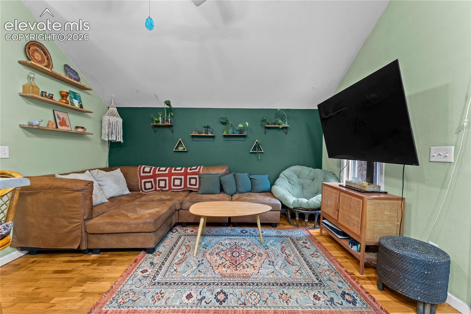 Vaulted ceiling, wood-finish flooring, and wall-mounted shelving units