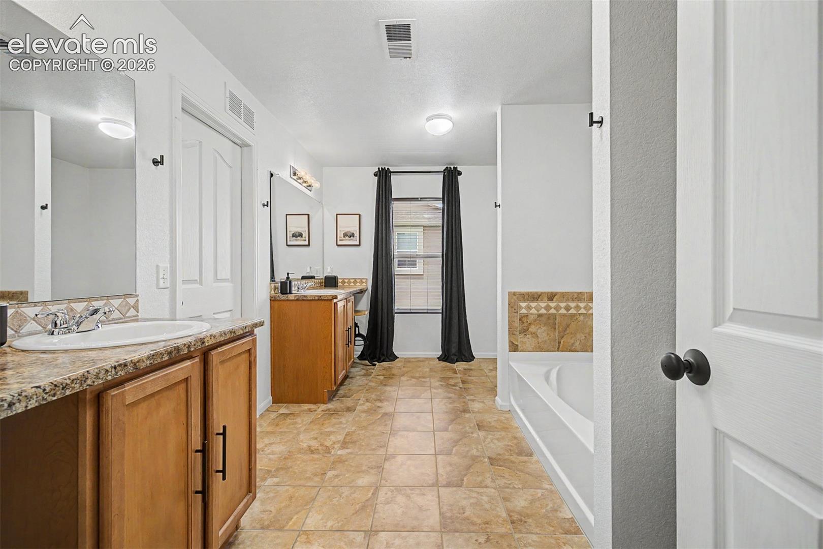 The depth of this primary bathroom is remarkable — with separate vanity zones, a dedicated soaking tub alcove, and a glass-enclosed shower, every inch of space has been put to purposeful use.