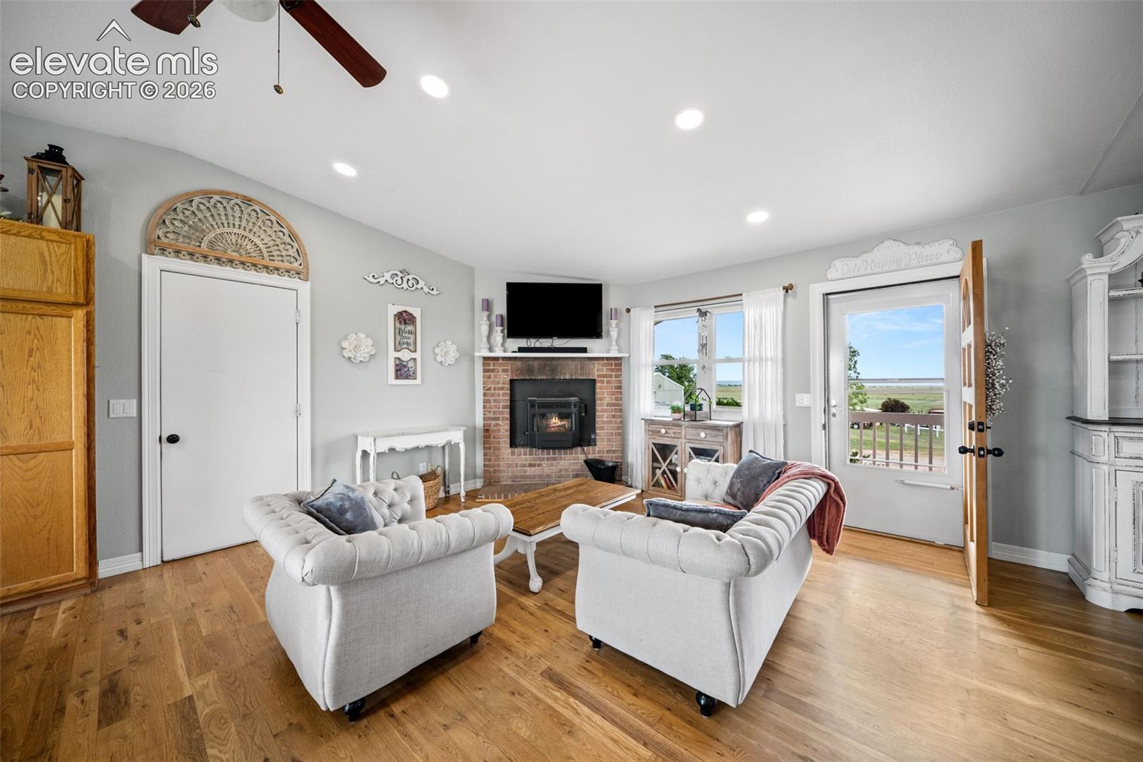 Living area featuring wood-finish flooring, a brick fireplace, recessed lighting, and a ceiling fan