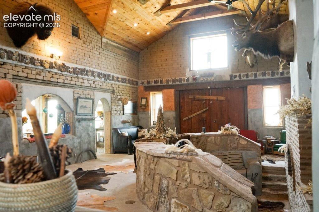 Vaulted wood-paneled ceiling with exposed beams, adobe brick walls, and stone accents