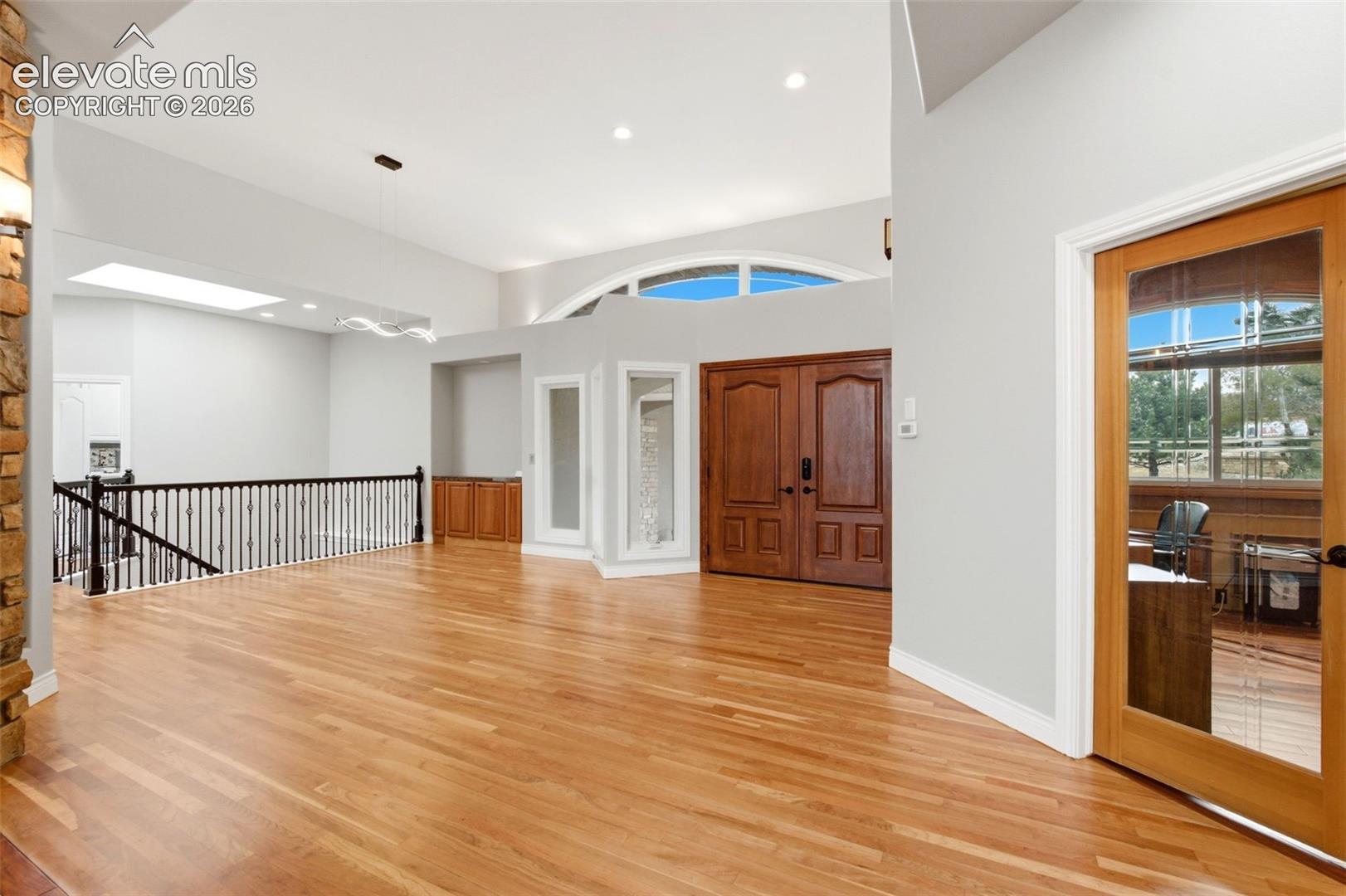 High ceilings, wood-finish flooring, double entry doors, an arched window, and a skylight