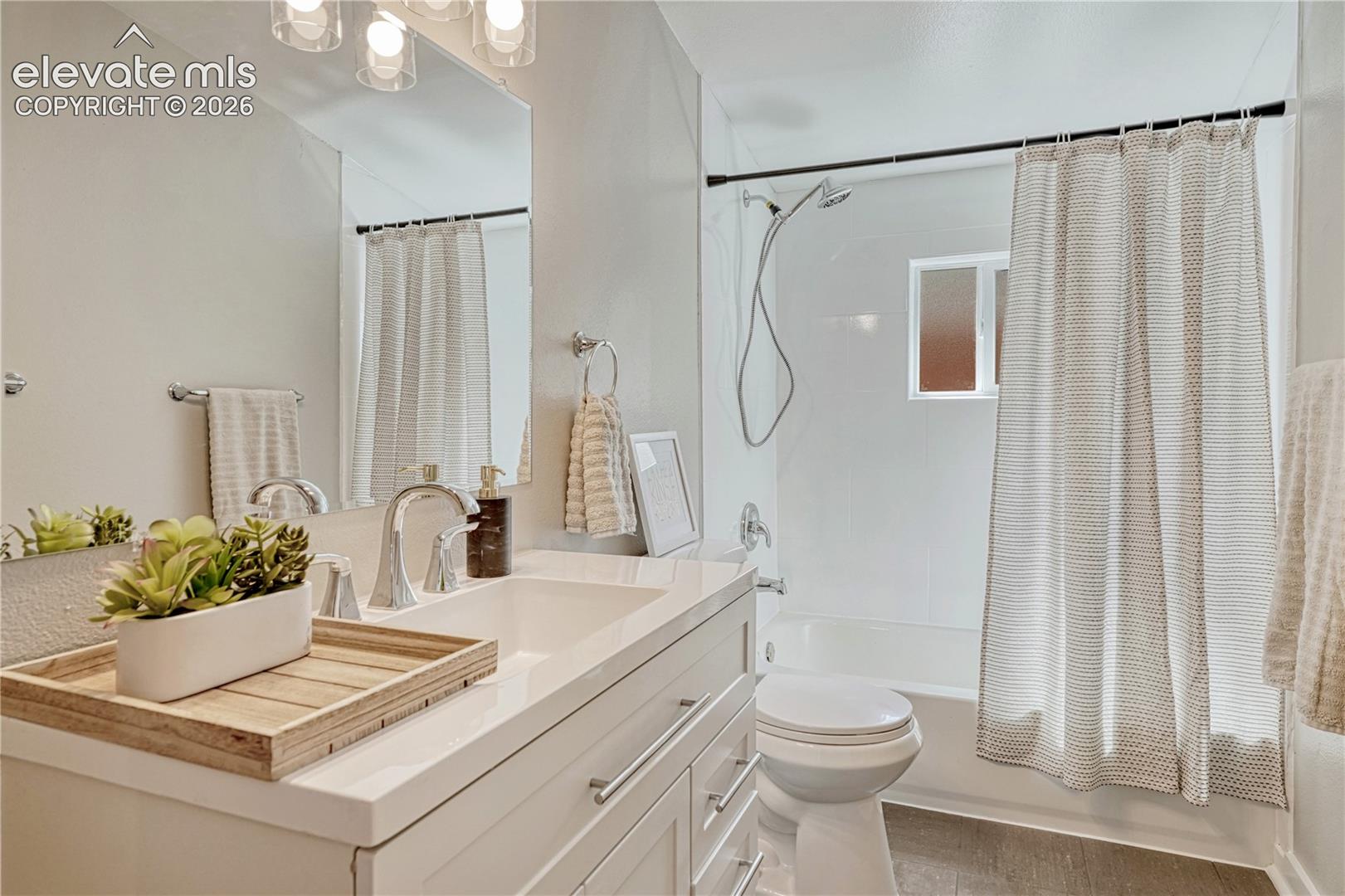 Spa-inspired bathroom featuring a floating vanity with quartz countertop and rectangular vessel sink, oversized framed mirror, walk-in shower with glass enclosure and neutral tile surround, and chrome fixtures throughout