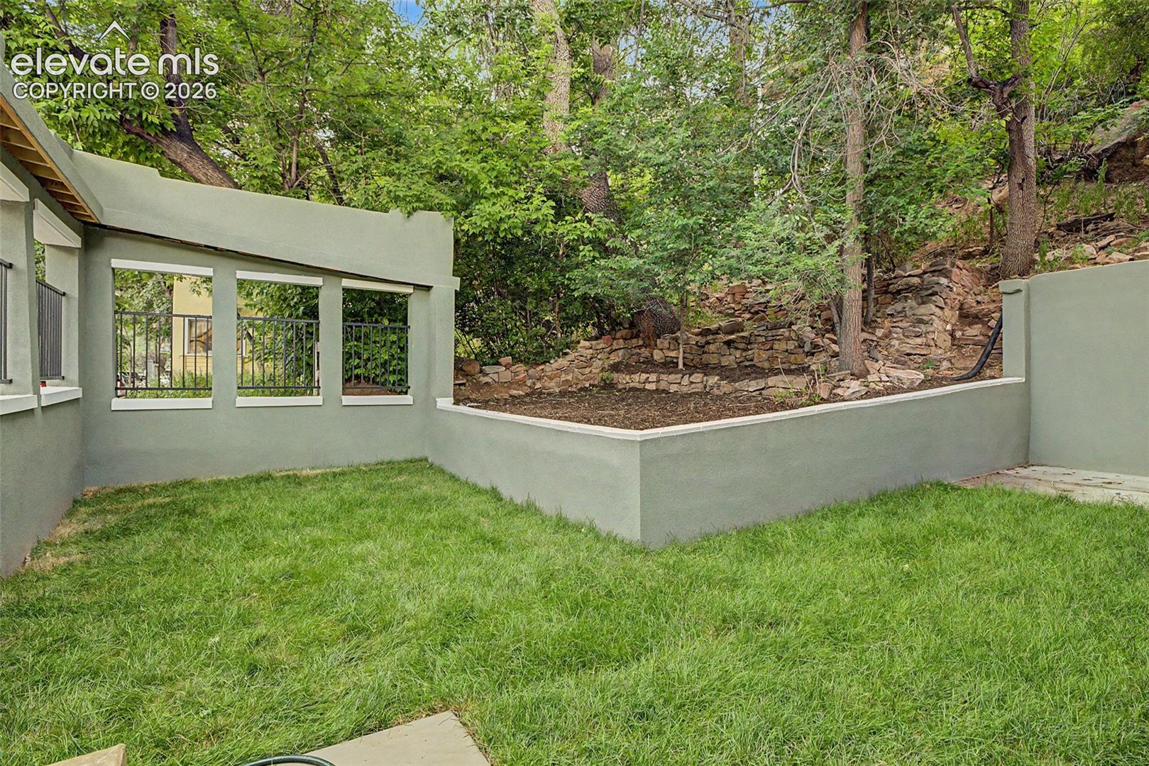 Private outdoor space featuring a stucco wall, integrated planter box, and stone retaining wall