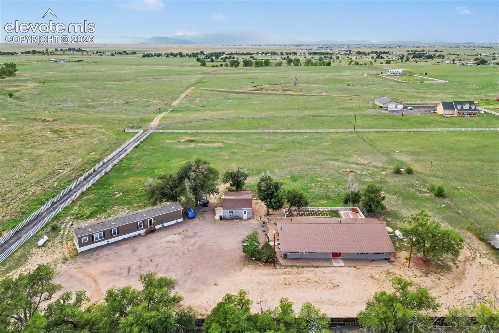 Stunning aerial perspective showcases the expansive property, two homes, abundant parking, open space, mature trees and mountain views only 35 mins to the heart of Downtown Colorado Springs