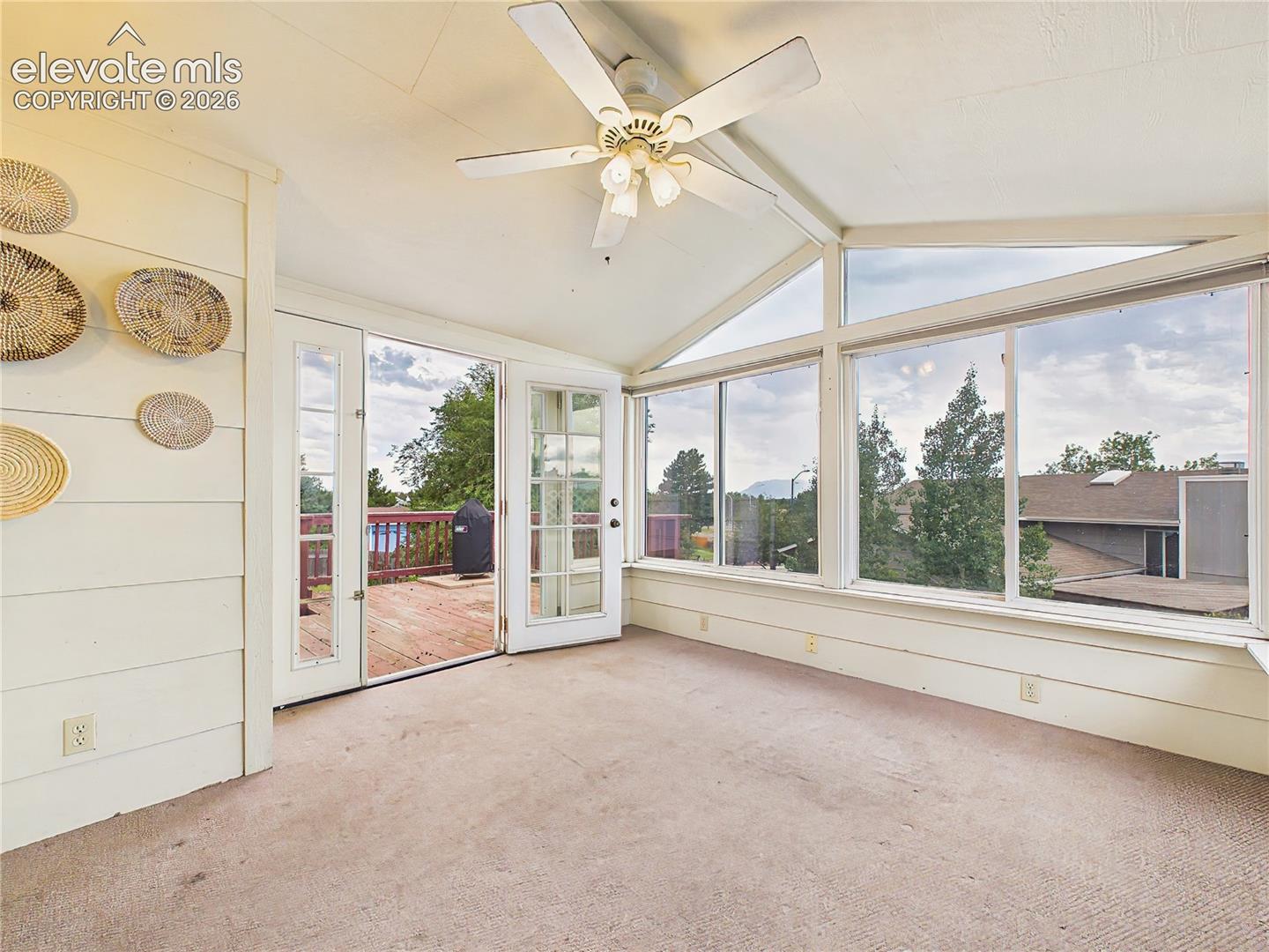 Bright enclosed sunroom surrounded by expansive windows, creating a versatile space to relax, enjoy the views, or use as a reading room, home office, or hobby space.