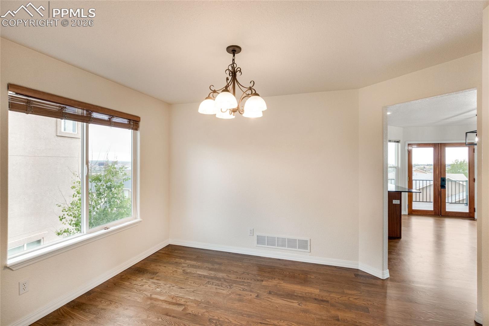 Dining area featuring wood-finish flooring, a large window with wood blinds, and an arched entryway