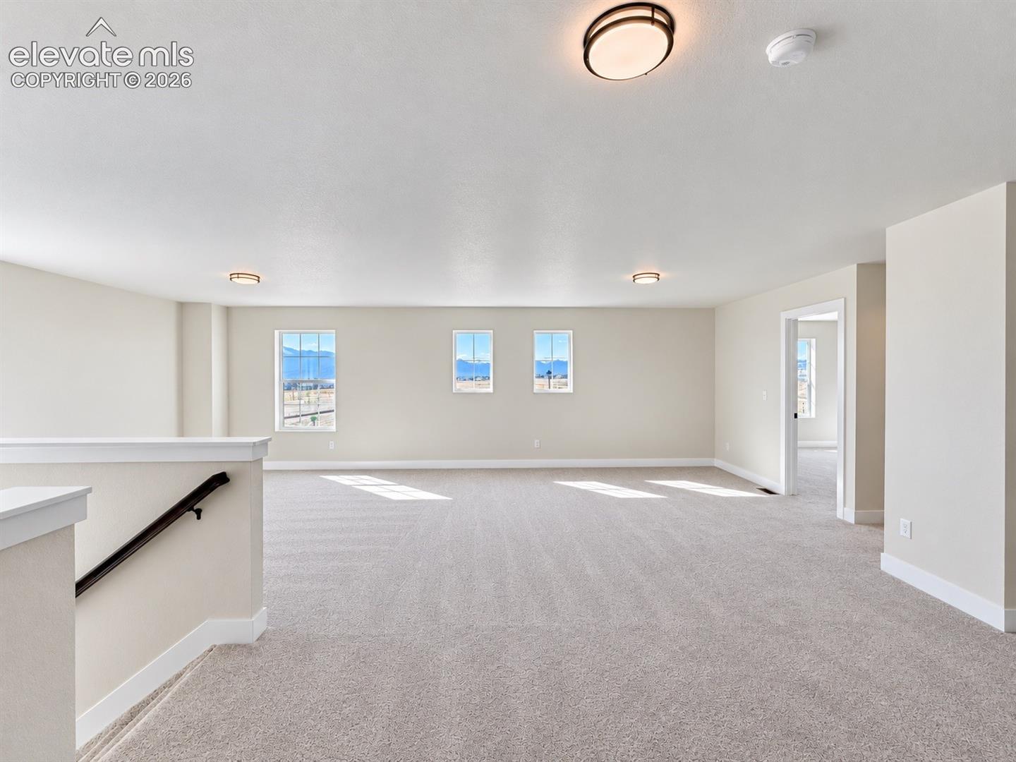 Expansive carpeted room featuring multiple windows, neutral wall tones, and recessed lighting fixtures