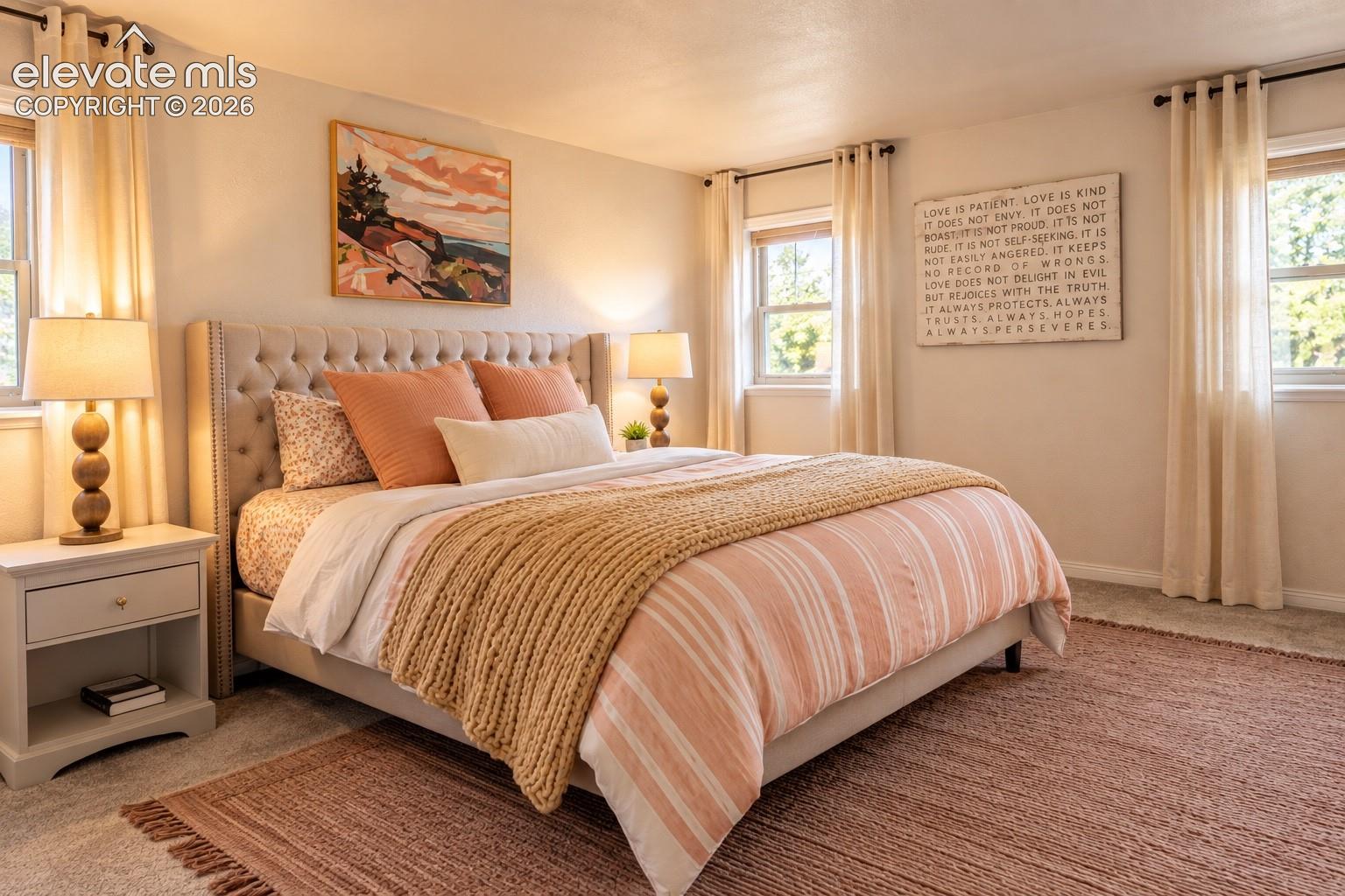 Tufted upholstered headboard, multiple windows, soft wall-to-wall carpeting, and light-toned walls