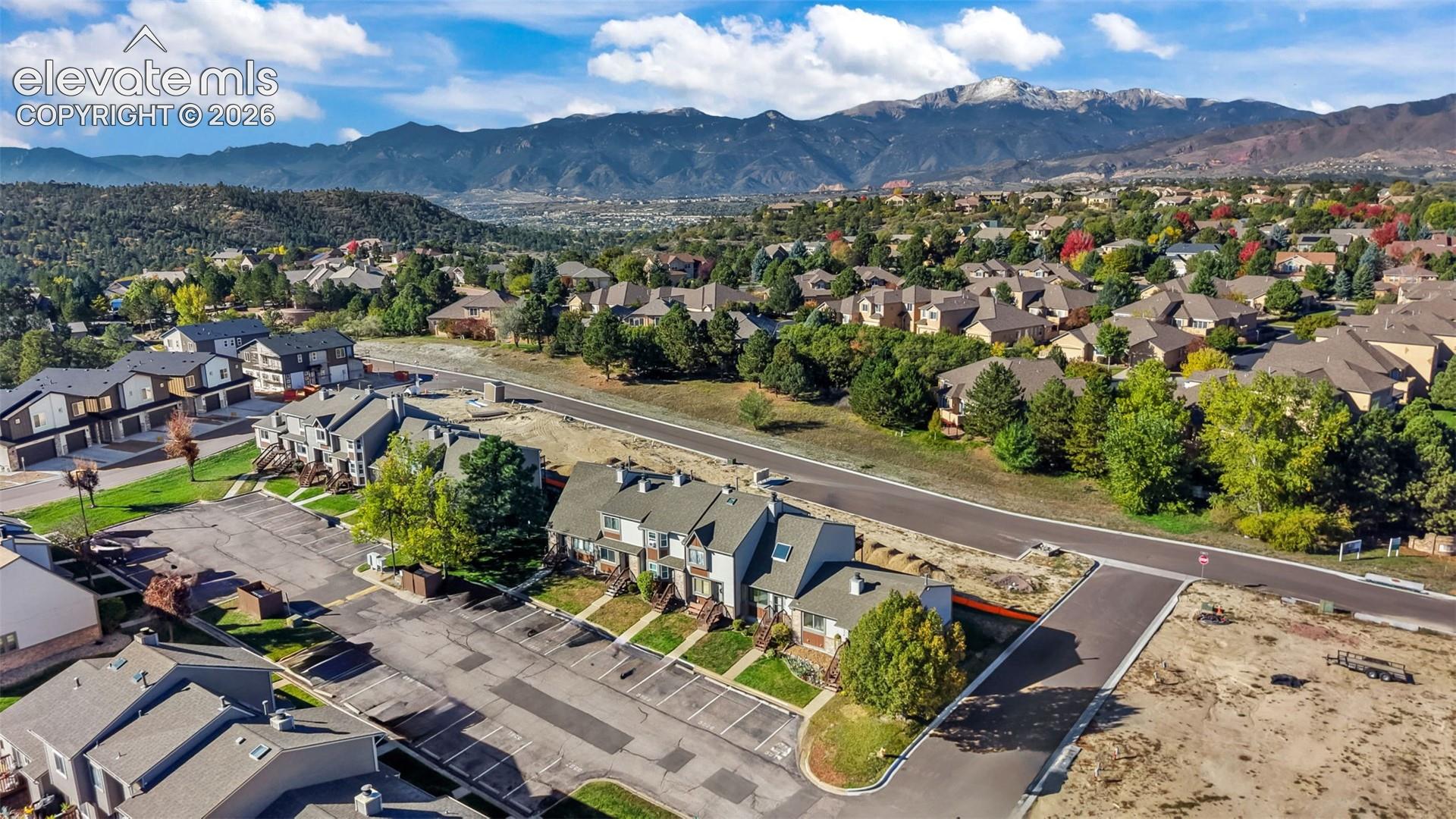 Multi-level residential community featuring peaked rooflines, paved parking areas, and expansive mountain range scenery