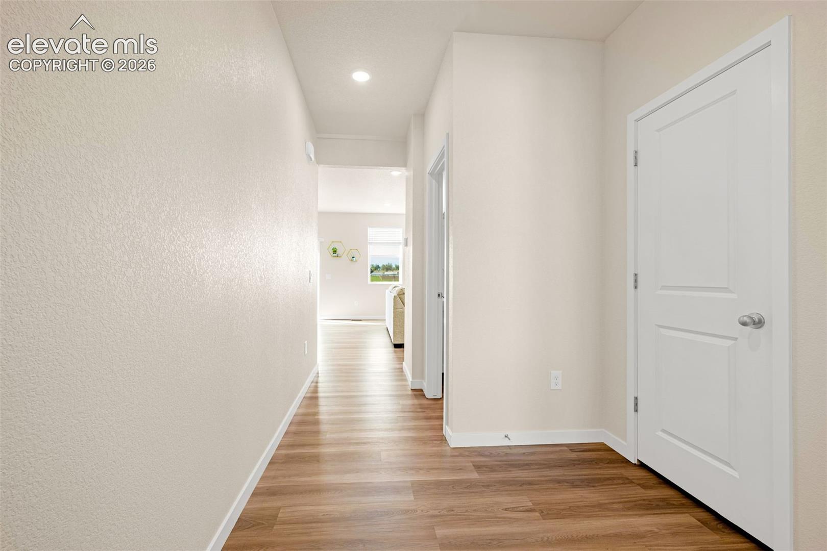 Wood-finish flooring, recessed lighting, and crisp white trim