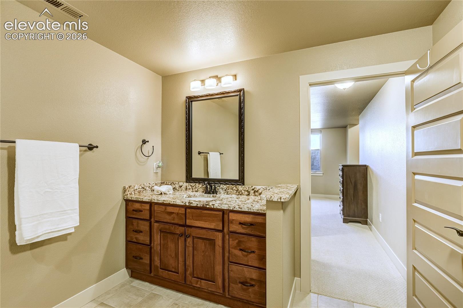 The garden-level full bath features a granite-topped vanity, custom cabinetry + a separate shower and soaking tub, providing comfort + convenience for the two lower-level bedrooms.