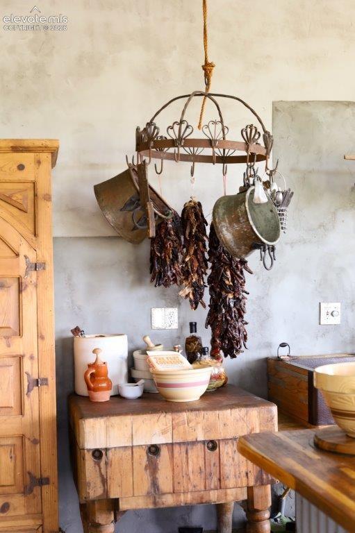 Butcher block island with turned wood legs, featuring a rustic wooden cabinet and an overhead wrought iron pot rack