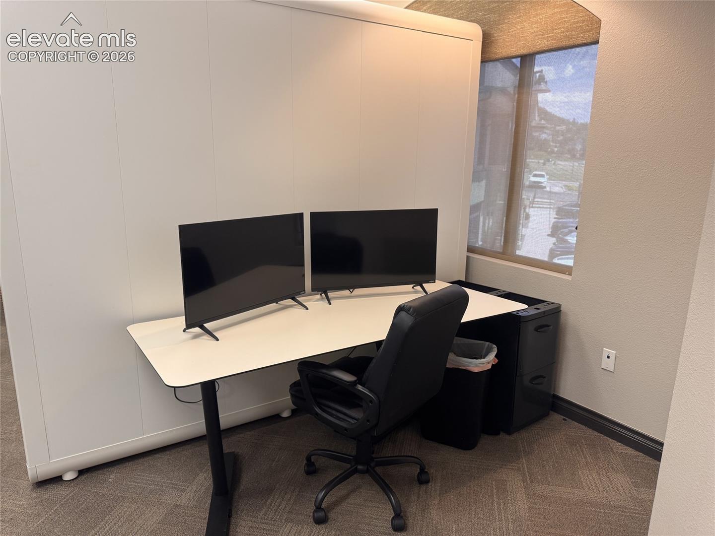 Window with horizontal blinds, textured wall finish, and commercial-grade carpet