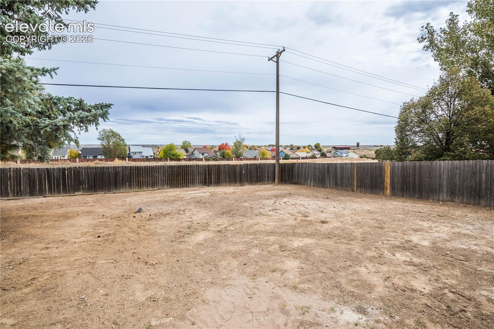 Open backyard enclosed by a wood privacy fence featuring mature trees
