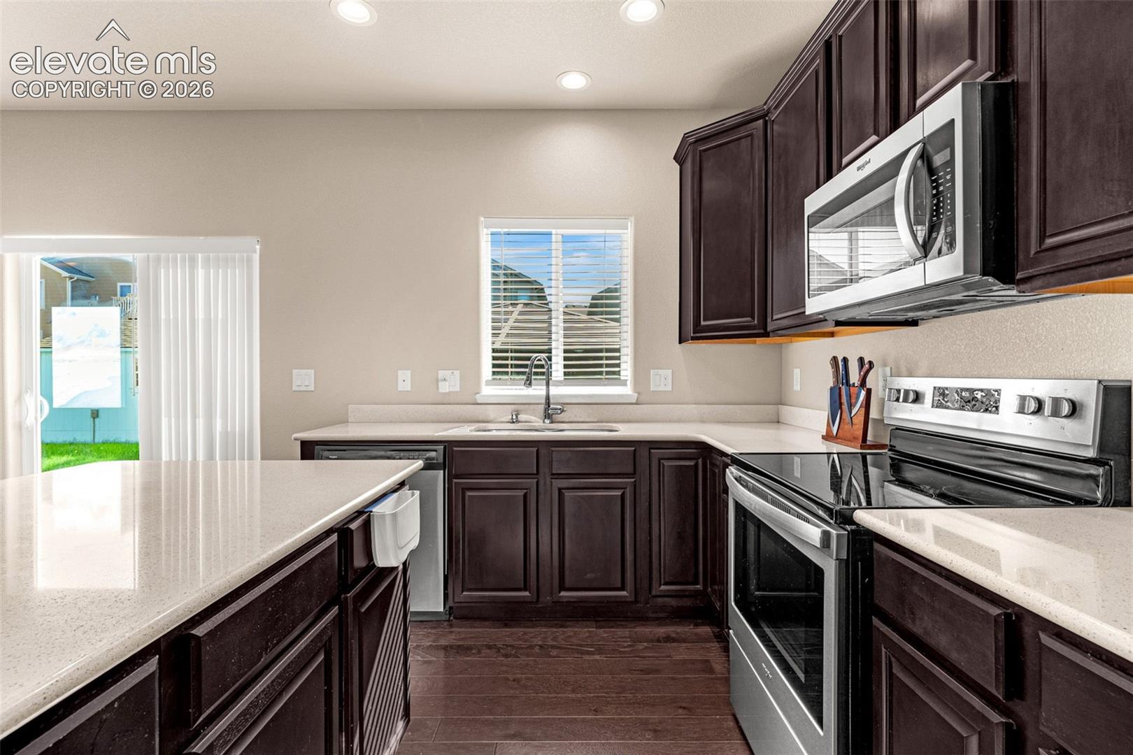 Rich wood-finish cabinetry, light-toned countertops, and stainless steel appliances