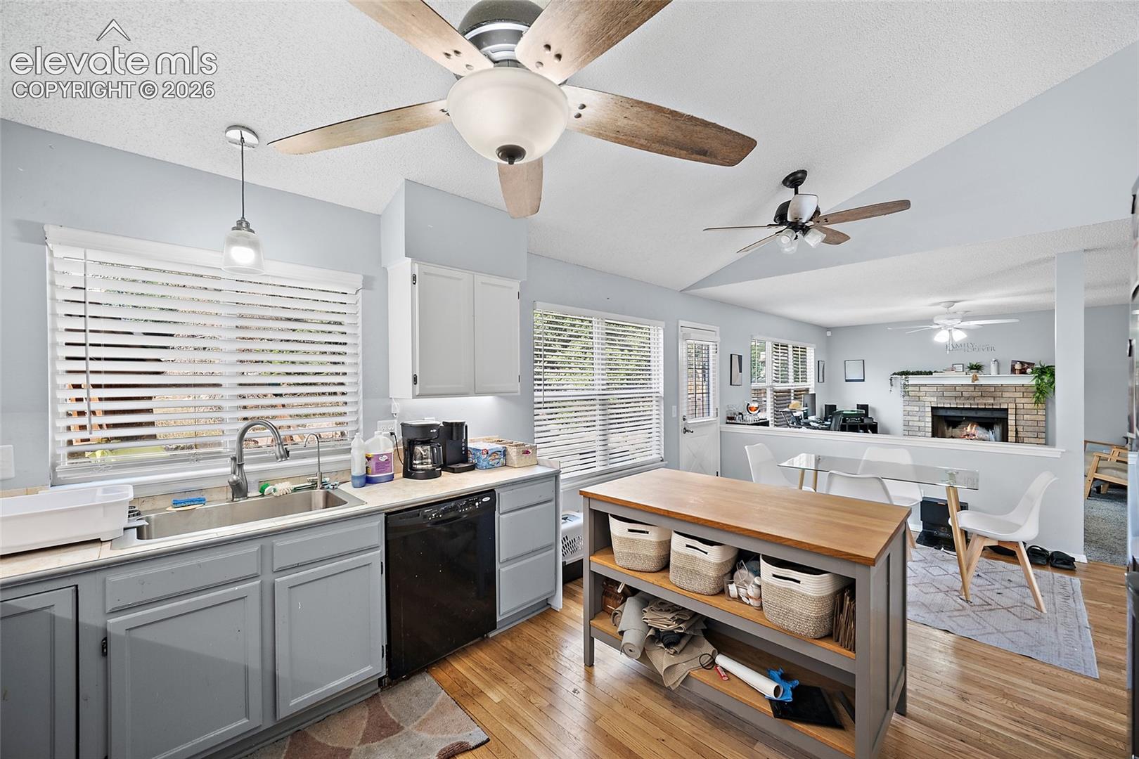 Kitchen featuring light wood-finish flooring, a central island with wood countertop, built-in ceiling fans, and light-toned cabinetry
