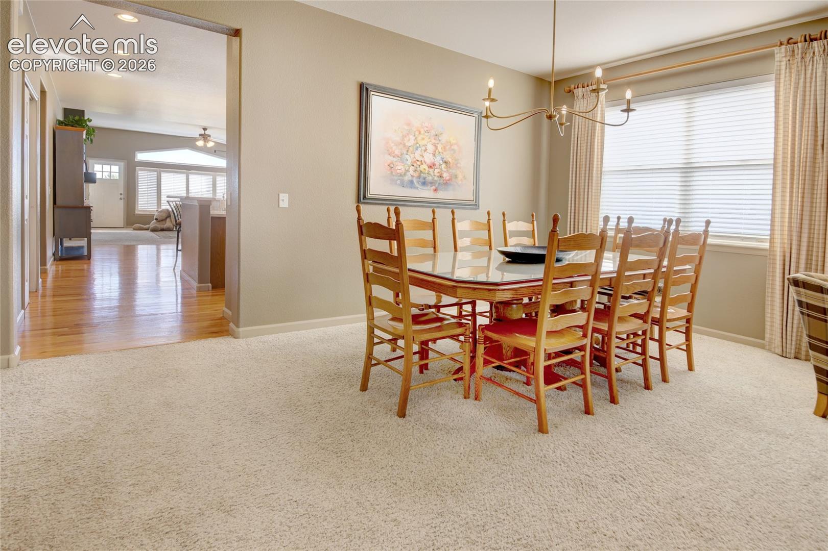 Dining area featuring neutral wall tones, wall-to-wall carpeting, and a multi-arm suspended chandelier